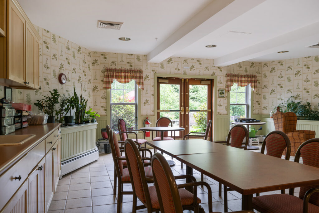 DSC01580-11209746 - Dirigo Pines Cozy dining area with a large wooden dining table and beautiful natural light at Dirigo Pines, offering a retreat for residents enjoying senior living near Bangor, ME.