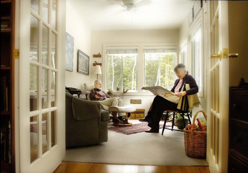 PickeringPorch2 - Dirigo Pines Residents sit in their living room / sitting room reading the newspaper with views of the forest outside their windows at Dirigo Pines senior living near Bangor, ME.